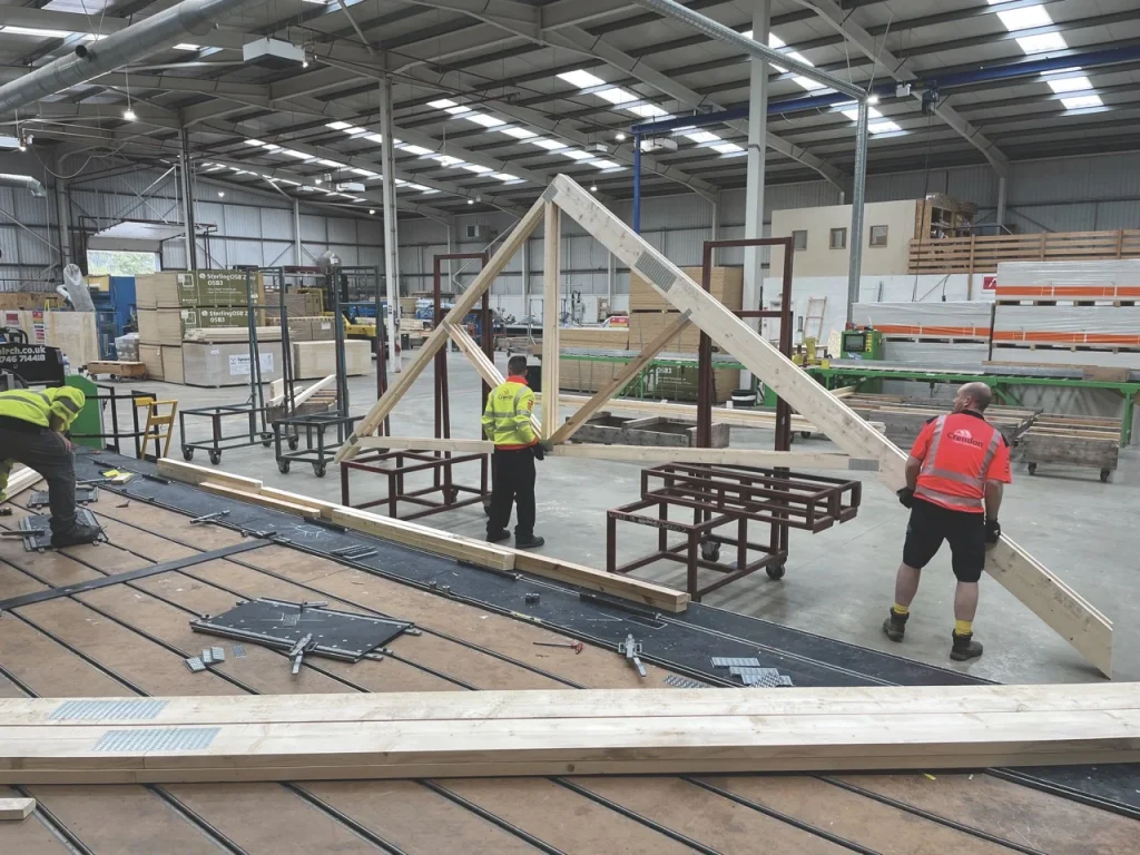 Men lifting roof truss in factory
