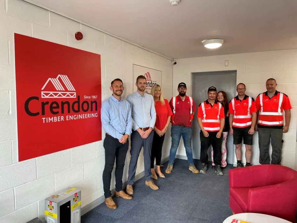 Team of people posing for photo next to Crendon Timber Engineering logo