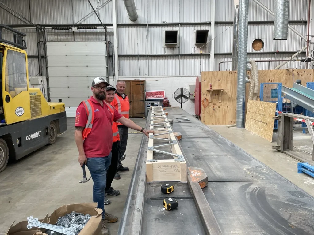 Men posing with posi joist in factory